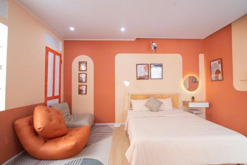 a bedroom with orange walls and a bed and a chair at An Du Boutique Stay in Dong Hoi