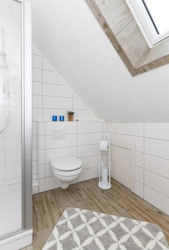 a white bathroom with a toilet in a attic at Haus Seemöwe Obergeschoss in Wittmund