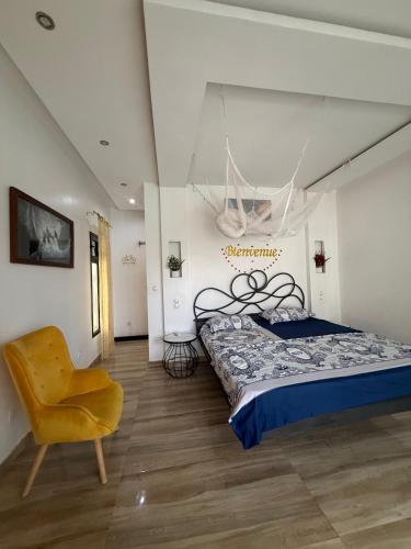 a bedroom with a bed and a yellow chair at Paradis in Ngaparou