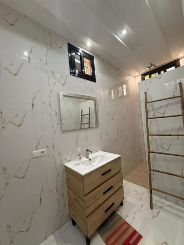 a bathroom with a sink and a marble wall at Paradis in Ngaparou