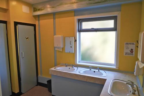 a bathroom with two sinks and a window at Loch Ness Lochside Hostel - Over 16s Only in Invermoriston