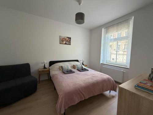 a bedroom with a bed and a couch and a window at Apartament between the bridges II in Zgorzelec