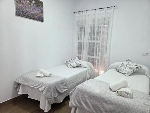 two beds in a room with a window at El Zamora in Sanlúcar de Barrameda