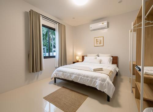 a white bedroom with a bed and a window at Nirvana Phangan Villas - Luxury & Serenity in Wok Tum