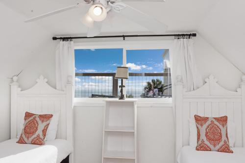 a white bedroom with two beds and a window at Latitude Adjustment by Pristine Properties Vacation Rentals in Indian Pass