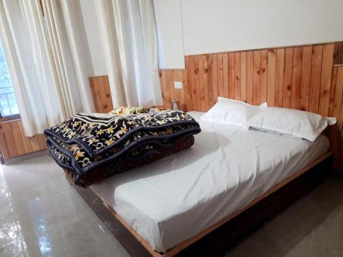 a bedroom with a large bed with a wooden headboard at Dholadhar Hotel & Restaurant in Barot 