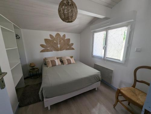 a bedroom with a bed and a window and a chair at Maisonnette chez Laurette in Saint-Martin-de-Seignanx