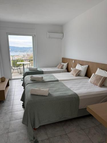 three beds in a room with a large window at Sea View Luxury Studios in Vrachonisída Palaiókastro