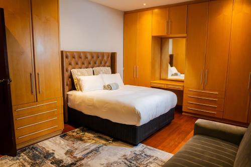 a bedroom with a bed with wooden cabinets and a couch at AB&AB Guesthouse Bedfordview in Germiston