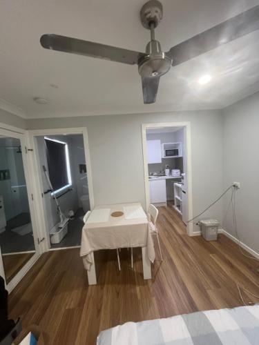 a white room with a table and a ceiling fan at Coomera Private Rooms near DreamWorld in Gold Coast