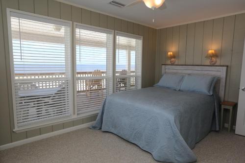 a bedroom with a bed and windows with a balcony at One More Time Again by Pristine Properties Vacation Rentals in Mexico Beach