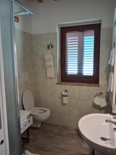 a bathroom with a toilet and a sink and a window at Masseria Spadone in Civitella Casanova