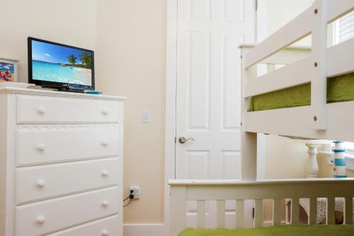 a bedroom with a white dresser with a tv on top at Waterside Village Cottage 3220 by Pristine Properties Vacation Rentals in Mexico Beach