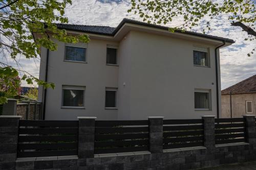 a white house with a fence in front of it at LG Apartman Siófok in Siófok