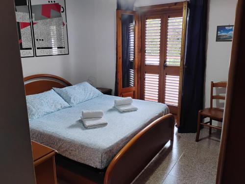 a bedroom with a bed with two towels on it at Casa delle Rose Terrazza vista mare panoramica e relax a Cala Gonnone, WiFi, AC in Cala Gonone