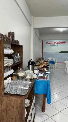 a buffet line with a blue table with plates and food at Hotel Polonini in Piúma