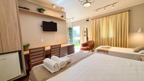 a hotel room with two beds and a flat screen tv at O Recanto Pousada in Serra Negra