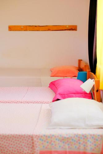 a bedroom with a bed with pink pillows at Simabo's Backpackers' Hostel in Mindelo