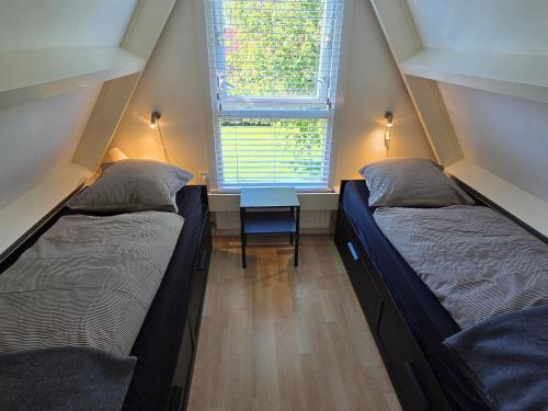 two beds in a small room with a window at View at the Lake in Nieuwe-Niedorp