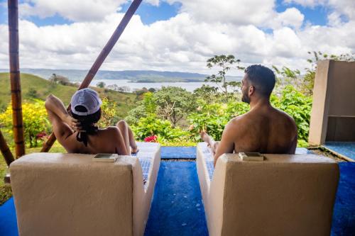 a man and a woman sitting on the edge of a pool at Essence Arenal Spa & Yoga in El Castillo de La Fortuna