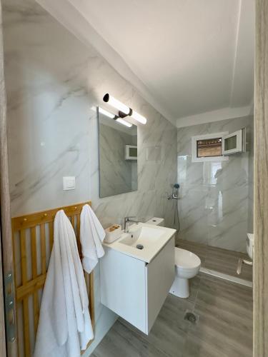 a white bathroom with a sink and a toilet at Rodia 1 in Pteleos