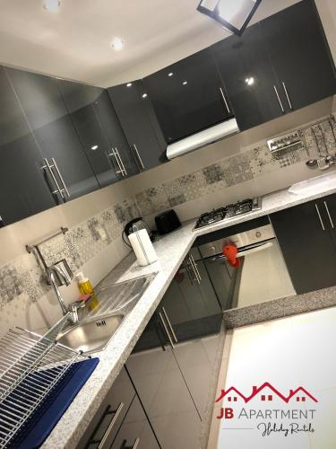 a kitchen with black cabinets and a sink at JB Apartment -B18- in Kenitra