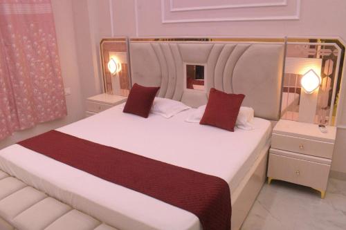 a bedroom with a large white bed with red pillows at Mehi villa in Ghaziabad