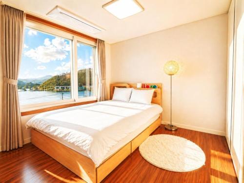 a bedroom with a bed and a large window at Chuncheon Kerensia Pension in Chuncheon