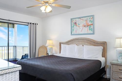 a bedroom with a bed with a ceiling fan and a balcony at Flamingo Dunes by Pristine Properties Vacation Rentals in Saint Joe Beach