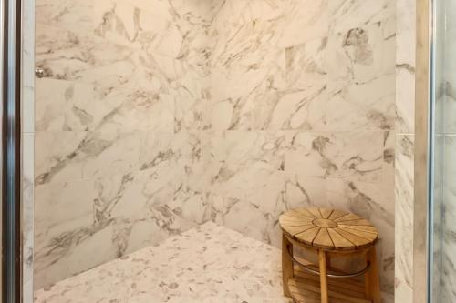 a bathroom with a white marble wall with a wooden stool at The Vue 2C by Pristine Properties Vacation Rentals in Mexico Beach