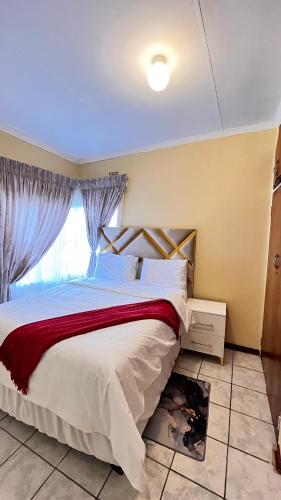 a bedroom with a large bed with a red blanket at Phumula Home in Mbabane