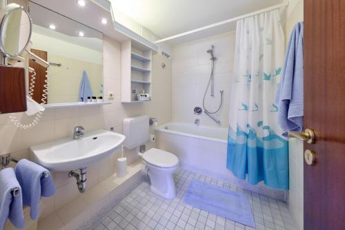 a bathroom with a sink and a toilet and a tub at Aparthotel Kachelot in Borkum