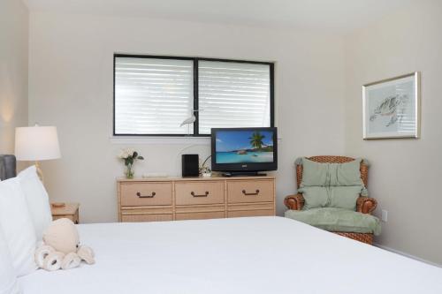 a bedroom with a bed and a tv and a chair at Woofs and Waves by Pristine Properties Vacation Rentals in Cape San Blas