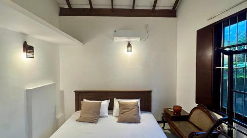 a bedroom with a bed with two pillows and a window at Induruwa Cottage in Induruwa