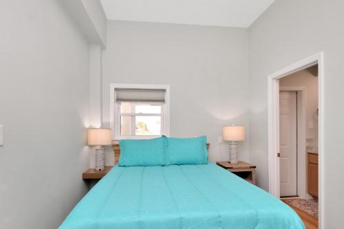 a blue bed in a white room with two lamps at Dolphin Daze Hideaway by Pristine Properties Vacation Rentals in Saint Joe Beach