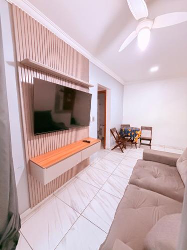 a living room with a couch and a flat screen tv at Apartamento Mirim Praia Grande in Praia Grande