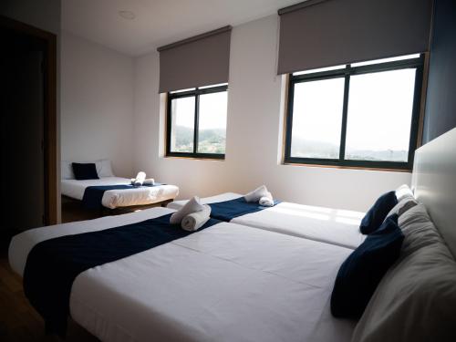 two beds in a room with two windows at Bahía de San Simón in Redondela