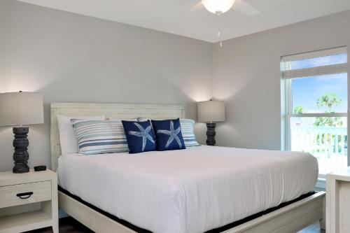 a white bed with blue pillows and a window at Pelican Roost A by Pristine Properties Vacation Rentals in Mexico Beach