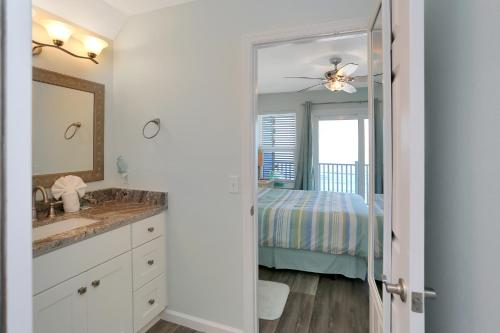 a bathroom with a sink and a bed and a mirror at Sandcastle C by Pristine Properties Vacation Rentals in Mexico Beach