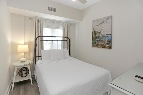 a white bedroom with a bed and a lamp at Summerhouse 209 by Pristine Properties Vacation Rentals in Mexico Beach
