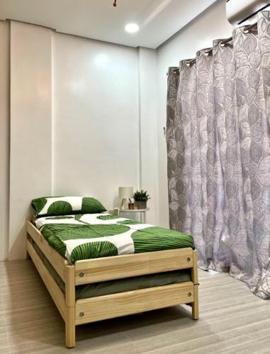 a bedroom with a bed with green and white sheets at Balay by JMB in Legazpi