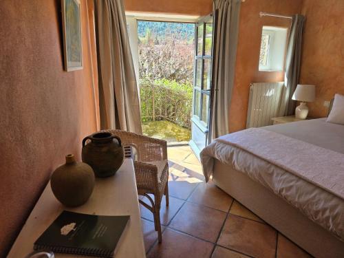 a bedroom with a bed and a table with a vase on it at La Maison de Piolon in Beaumont-du-Ventoux