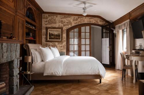 a bedroom with a white bed and a fireplace at Angelats Hotel - A Signature Boutique Hotel & Restaurant in Ribes de Freser