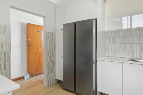 a kitchen with a stainless steel refrigerator and a wooden door at Coastal Condo Strand in Strand