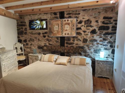 a bedroom with a bed and a stone wall at Casa Fabiana in Montenegro de Cameros