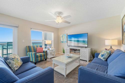 a living room with blue furniture and a flat screen tv at Spacious gulf front condo with beach access in Fort Walton Beach