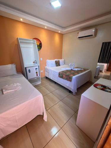 a hotel room with two beds and a table at Pousada Málaga in Porto De Galinhas