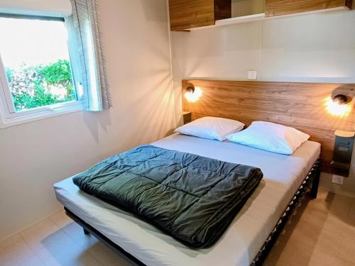 a bedroom with a bed with a wooden headboard and a window at Camping de la Tour AMBON in Ambon
