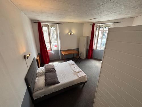 a small room with a bed and two windows at Le grand cerf Blain in Blain
