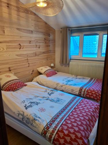 two beds in a room with wooden walls and windows at le sans soucis in Bellevaux